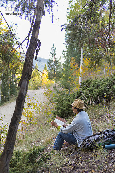 Ein Mann liest ein Buch auf einem ländlichen Hügel