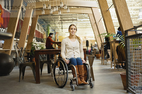 Querschnittsgelähmte Frau sitzt im Rollstuhl in einem Café