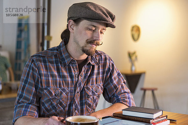 Kaukasischer Mann liest in einem Cafe