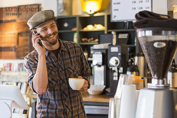 Kaukasischer Mann  der in einem Café mit seinem Handy telefoniert