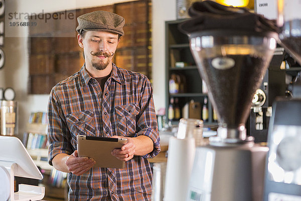 Kaukasischer Mann benutzt digitales Tablet in einem Café