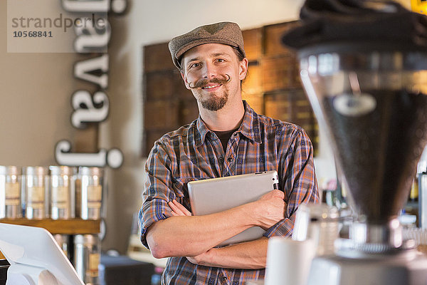 Kaukasischer Barista hält digitales Tablet in einem Cafe