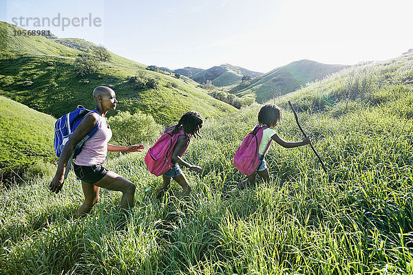Schwarze Mutter und Töchter gehen auf einem ländlichen Hügel spazieren
