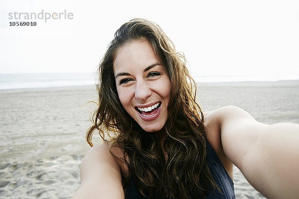 Gemischtrassige Frau macht Selfie am Strand