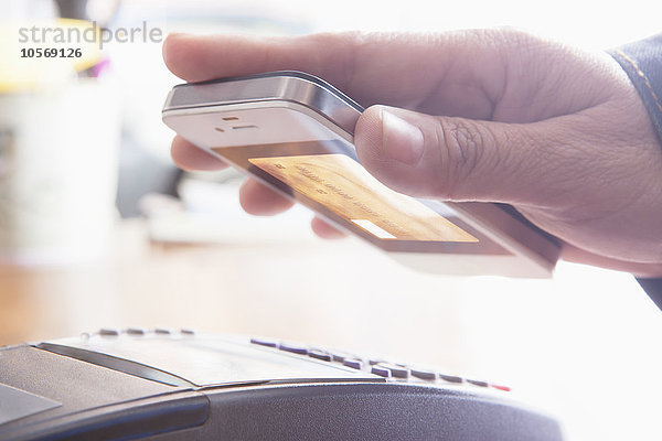 Hispanische Frau scannt Kreditkarte vom Mobiltelefon