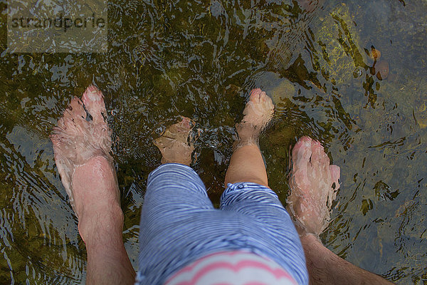 Vater und Tochter stehen barfuß im Wasser