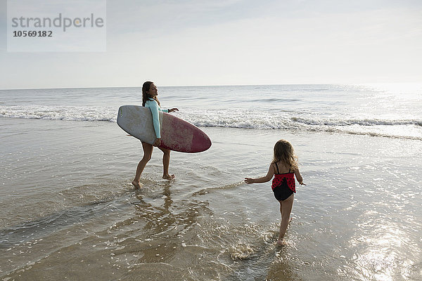 Mutter und Tochter spielen in den Wellen am Strand