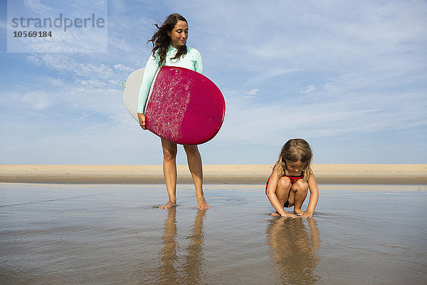 Mutter und Tochter spielen in den Wellen am Strand