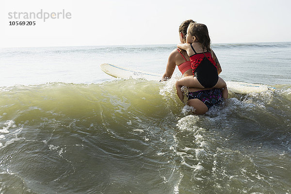 Mutter und Tochter surfen in den Wellen