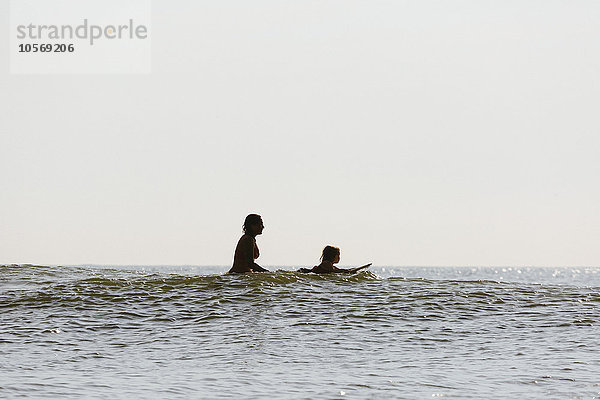 Mutter und Tochter surfen in den Wellen