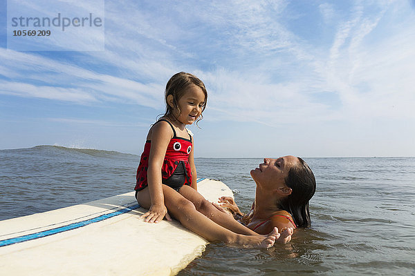 Mutter bringt Tochter das Surfen im Meer bei