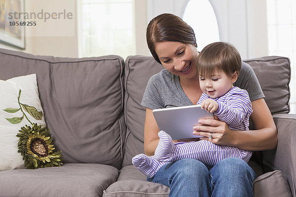 Gemischtrassige Mutter und ihre kleine Tochter benutzen ein digitales Tablet