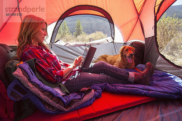 Kaukasische Frau benutzt digitales Tablet im Campingzelt