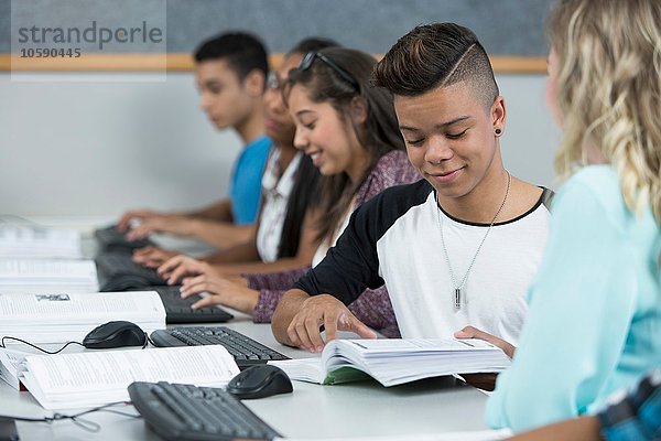 Reihe von jugendlichen Gymnasiasten  die zusammen in der Computerklasse arbeiten