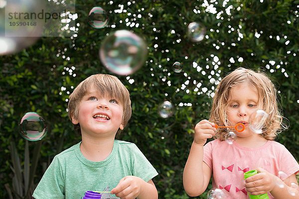 Junges Mädchen und Junge blasen Blasen  draußen