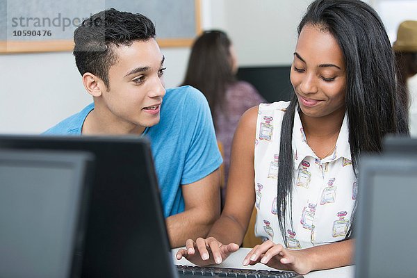 Zwei Teenager  die in der Highschool-Klasse am Computer tippen.