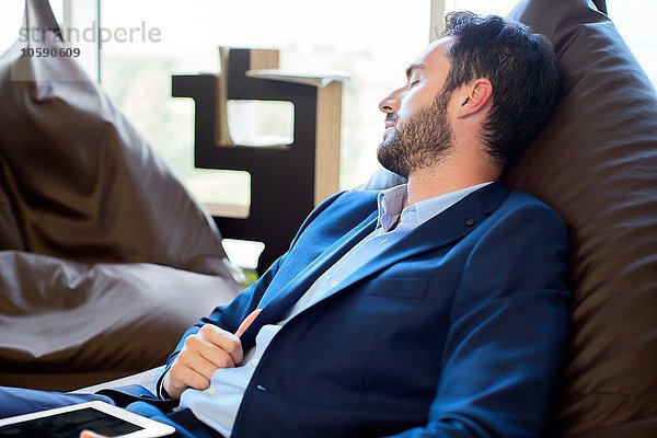 Jungdesigner schläft auf Sitzsackstühlen im Büro