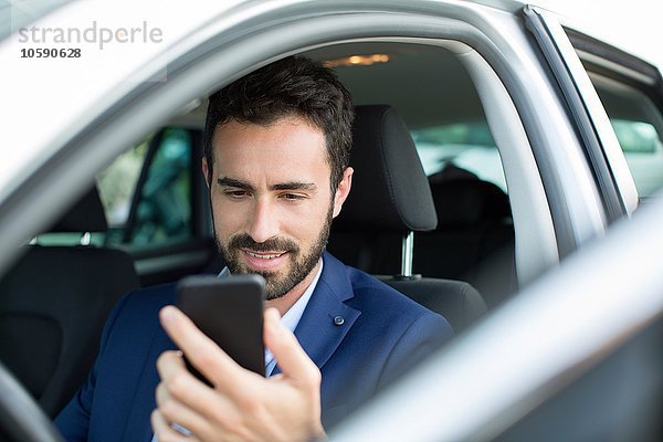 Jungunternehmer beim Lesen von Smartphone-Texten im Auto