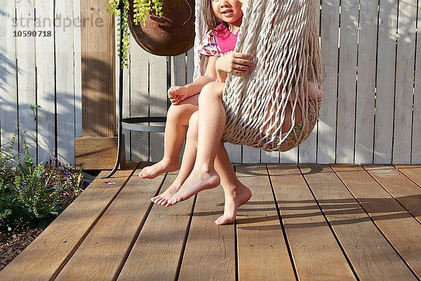 Mädchen sitzen in der Hängematte auf der Veranda