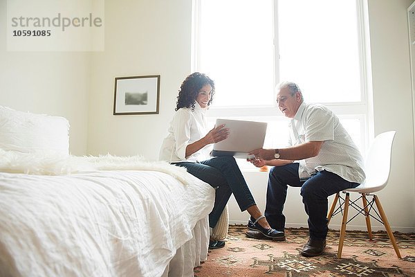Senioren-Paar mit Blick auf Laptop im Schlafzimmer