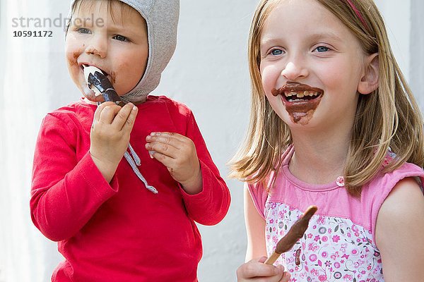 Weibliches Kleinkind und Schwester essen unordentlich Schokoladeneis