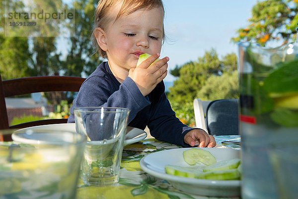 Weibliches Kleinkind beim Essen am Tisch im Freien
