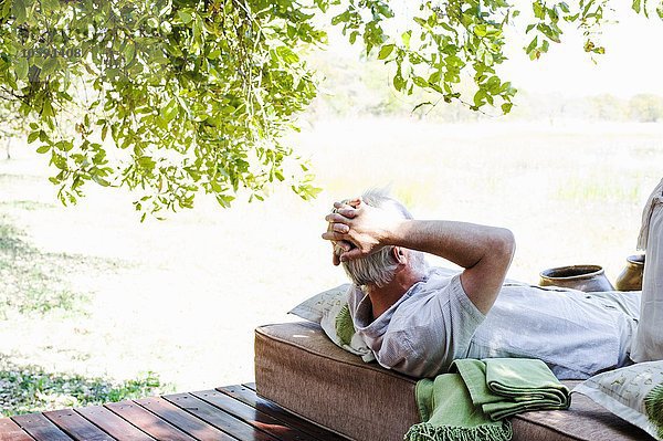 Senior-Mann entspannt sich auf der Liege in der Safari-Lodge  Kafue Nationalpark  Sambia