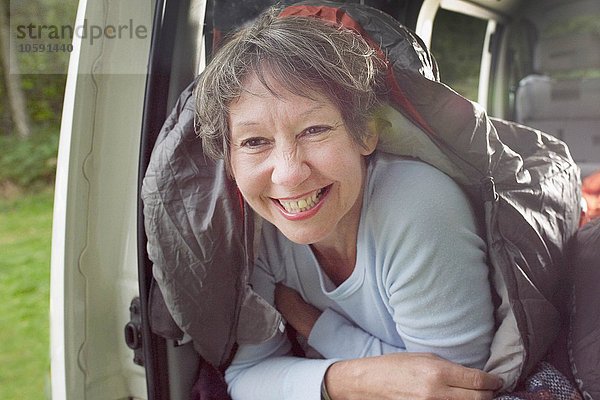 Porträt der Seniorin im Schlafsack  im offenen Wohnmobil