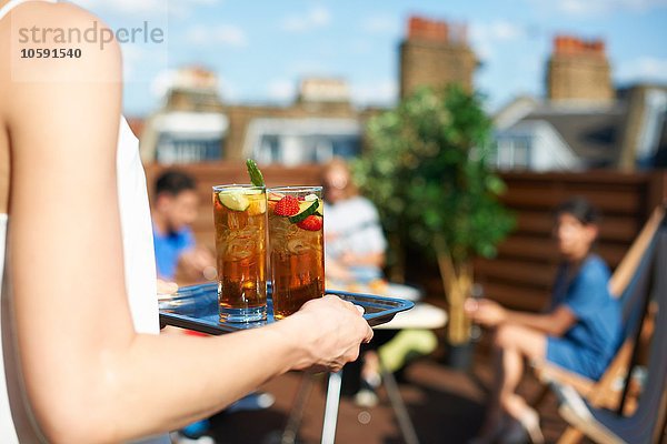 Frau trägt Tablett mit Cocktails auf der Dachparty