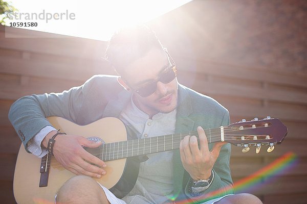 Mittlerer Erwachsener Mann spielt Gitarre auf der Dachparty