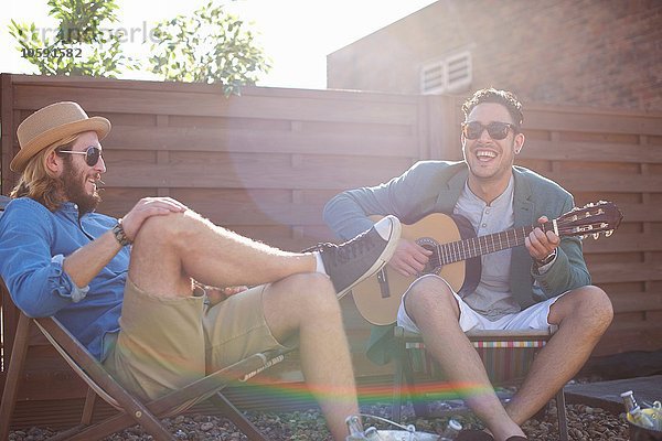 Zwei männliche Freunde beim Gitarrespielen auf der Dachparty