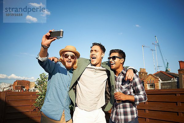 Drei männliche Freunde  die sich auf der Dachparty selbst fotografieren lassen