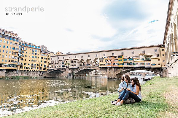 Lesbenpaar am Flussufer mit Blick auf Digitalkamera vor Ponte Vecchio und Arno  Florenz  Toskana  Italien