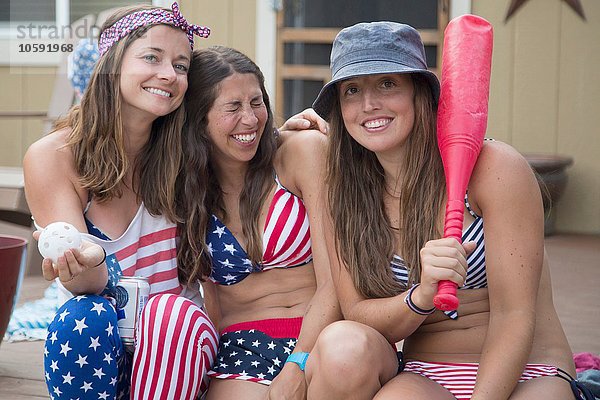 Porträt von drei jungen Frauen in amerikanischer Flagge zum Unabhängigkeitstag  USA