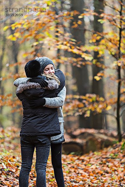 Mädchen umarmen sich im Herbstwald