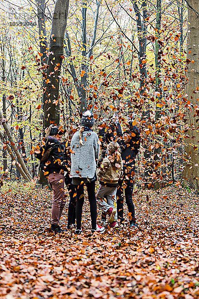 Mädchen spielen mit Blättern im Herbstwald