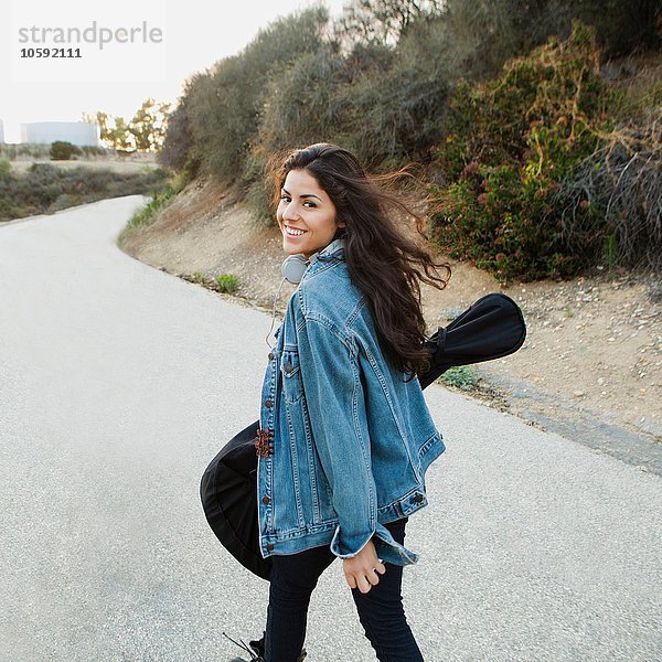 Junge Frau mit Gitarre  die über die Schulter schaut und lächelt  Woodland Hills  Kalifornien  USA