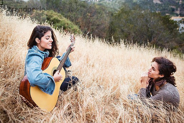 Junge Frau im langen Gras spielt Gitarre für Freund  Woodland Hills  Kalifornien  USA