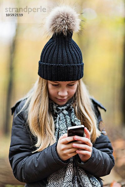 Mädchen mit Smartphone im Herbstwald