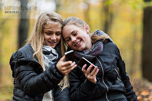 Mädchen mit Smartphone im Herbstwald