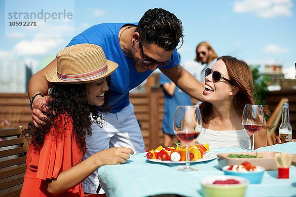 Männliche und weibliche Freunde beim Grillen auf dem Dach