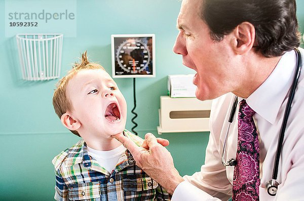 Kleiner Junge bei der Untersuchung in der Arztpraxis  Arzt schaut in den Mund des Jungen