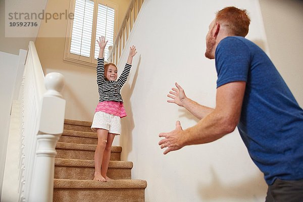 Mädchen bereitet sich darauf vor  auf der Treppe zu Hause in Vaters Arme zu springen.
