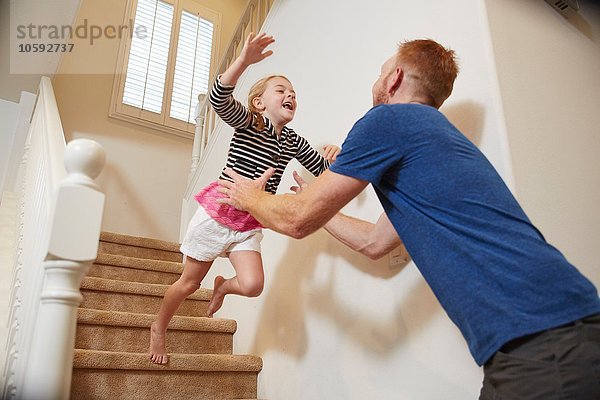 Mädchen springt in Vaters Arme auf der Treppe zu Hause