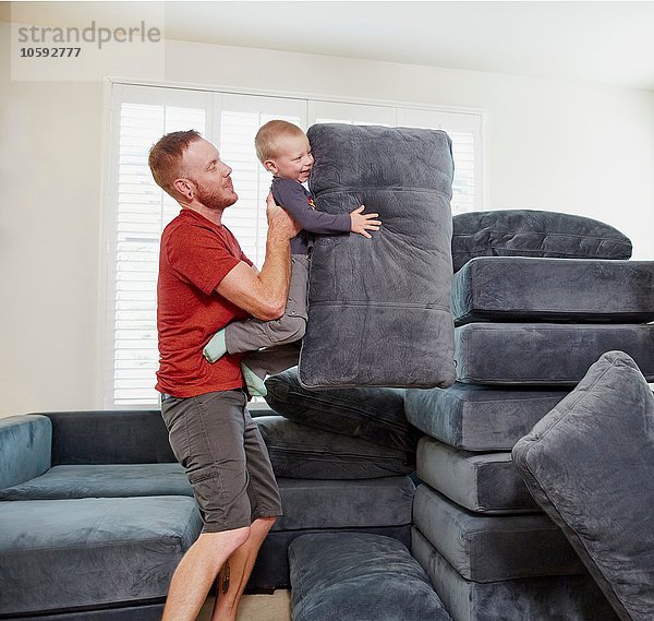 Vater und Sohn stapeln Kissen im Wohnzimmer