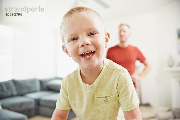 Junge lächelt im Wohnzimmer  Vater im Hintergrund