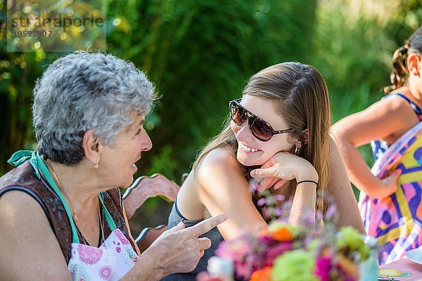 Mittlere erwachsene Frau im Gespräch mit älterer Frau im Garten