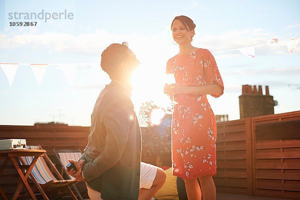 Mann schlägt Frau auf Dachterrasse vor  Sonnenuntergang im Hintergrund