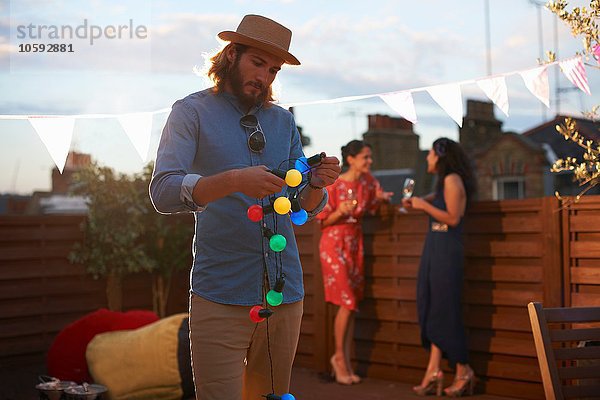 Mann hängende Gartenbeleuchtung für die Party am frühen Abend