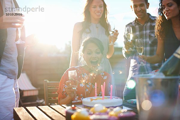 Freunde auf der Outdoor-Party beim Ausblasen von Kerzen auf Kuchen